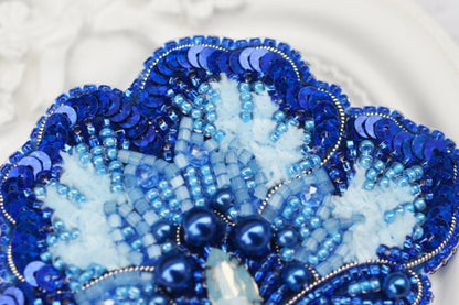 a close up of a blue and white beaded brooch