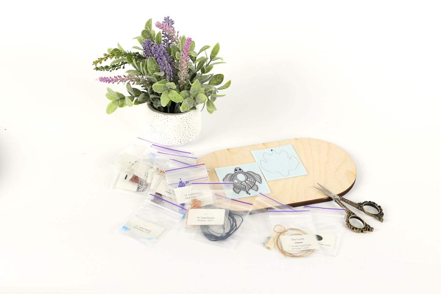 a potted plant, a wooden board, and various craft supplies such as zippers, scissors, and a piece of paper with a drawing.