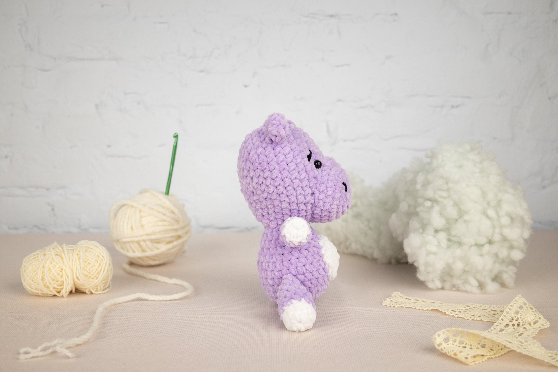 a purple crocheted animal next to a ball of yarn