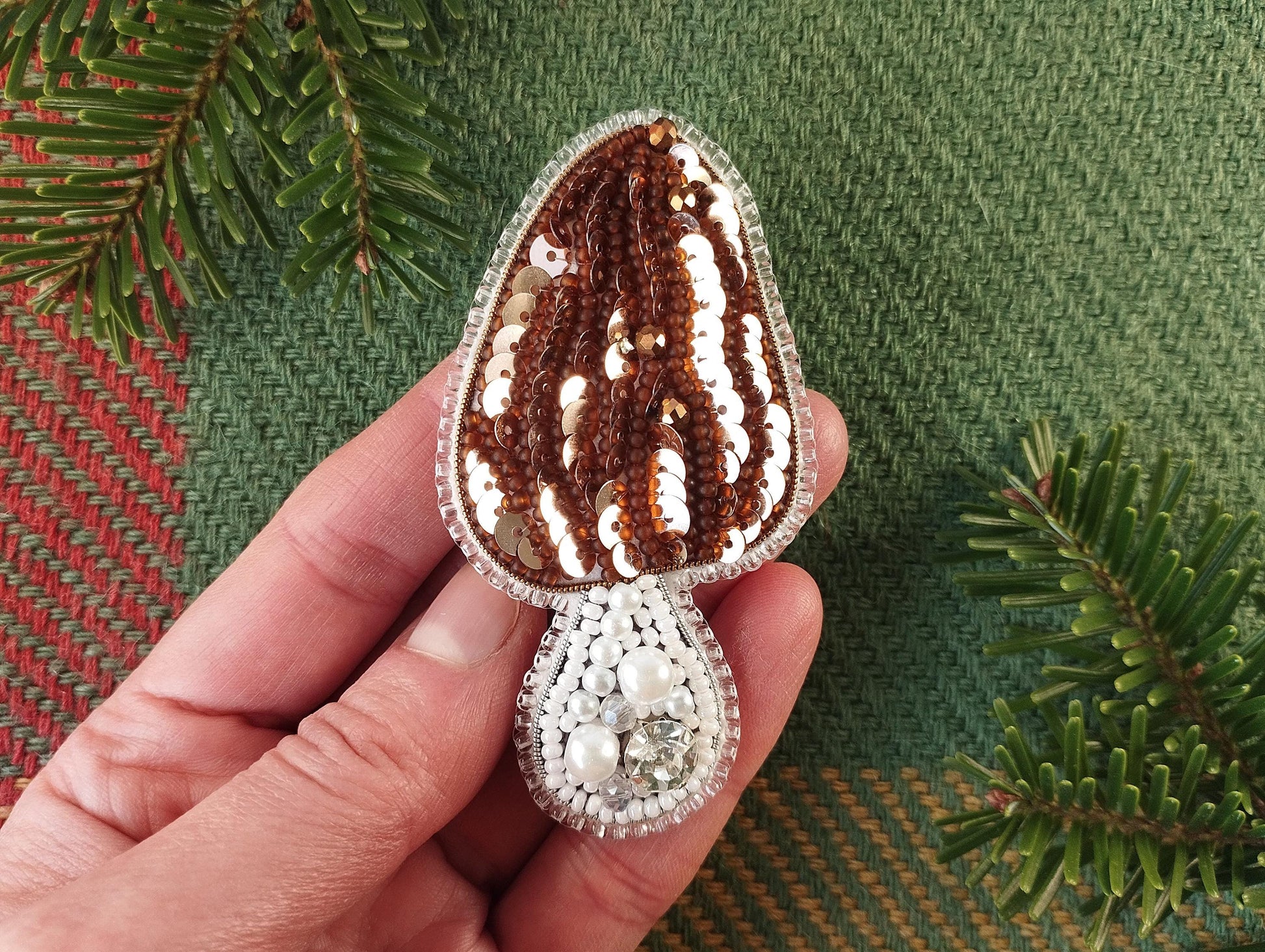 a hand is holding a brown and white brooch