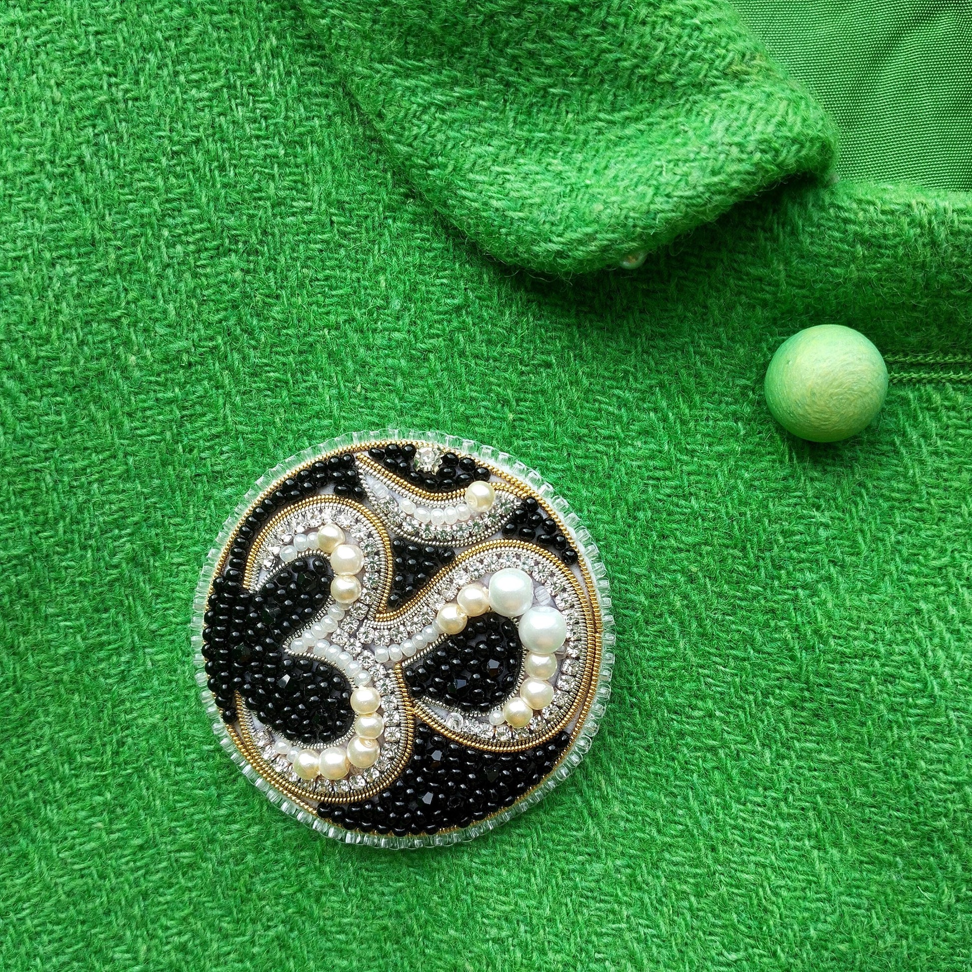 a close-up of a green fabric with a decorative brooch in the center.