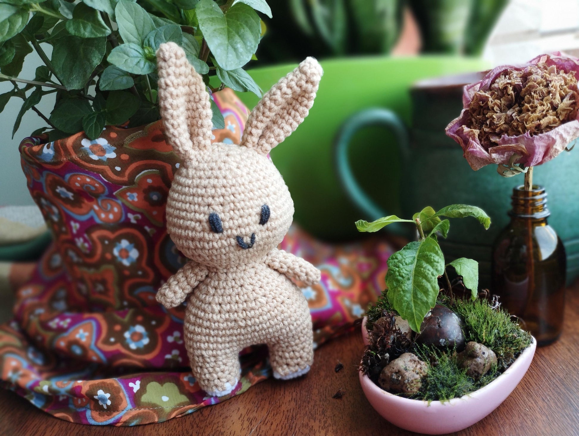 a crocheted bunny sitting next to a potted plant