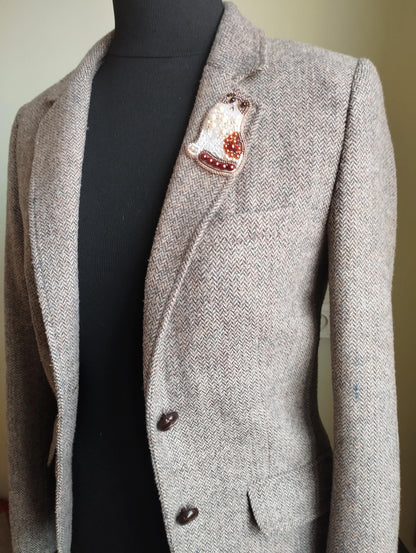 A gray tweed blazer with a decorative pin on the lapel.
