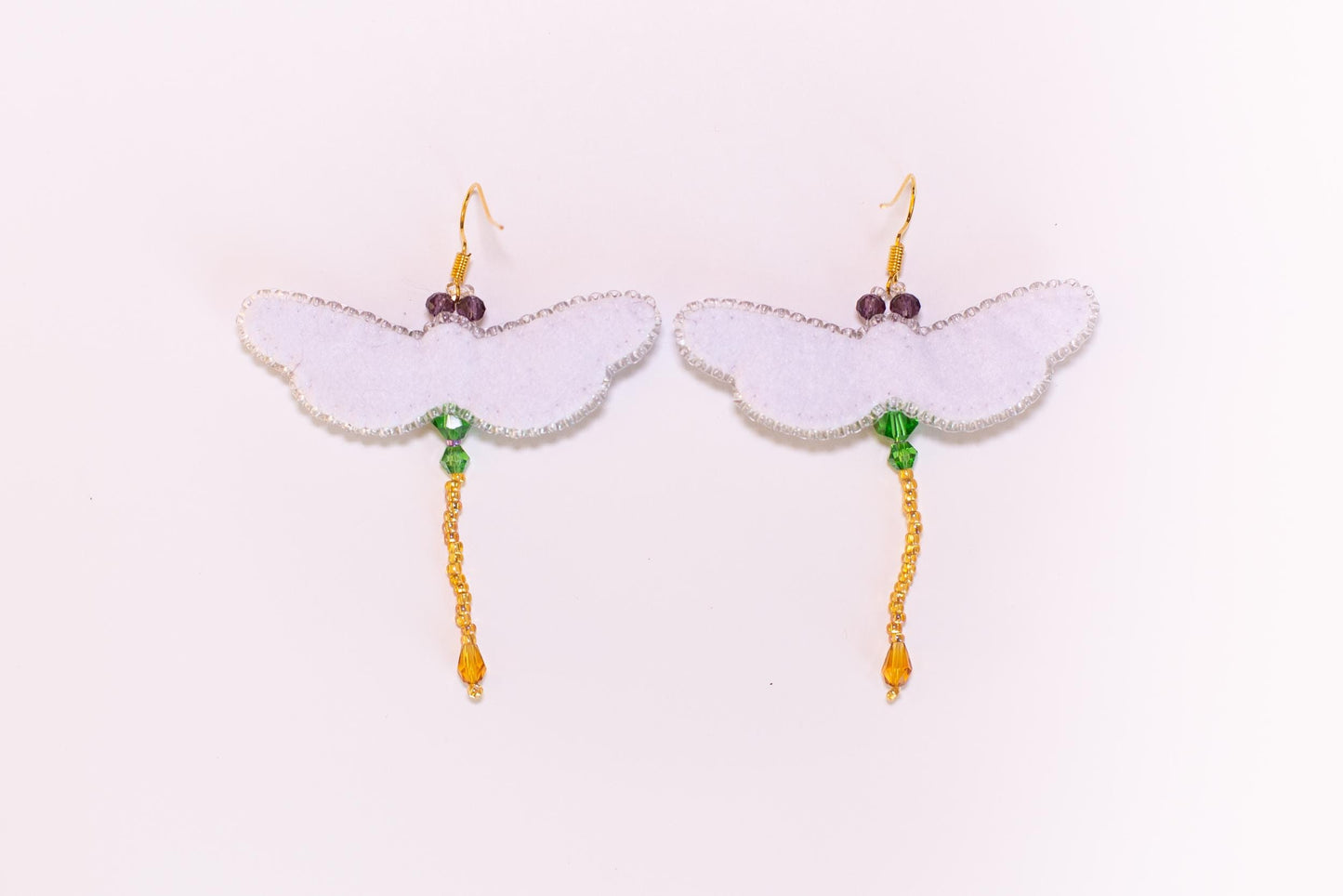 a pair of white earrings with green beads