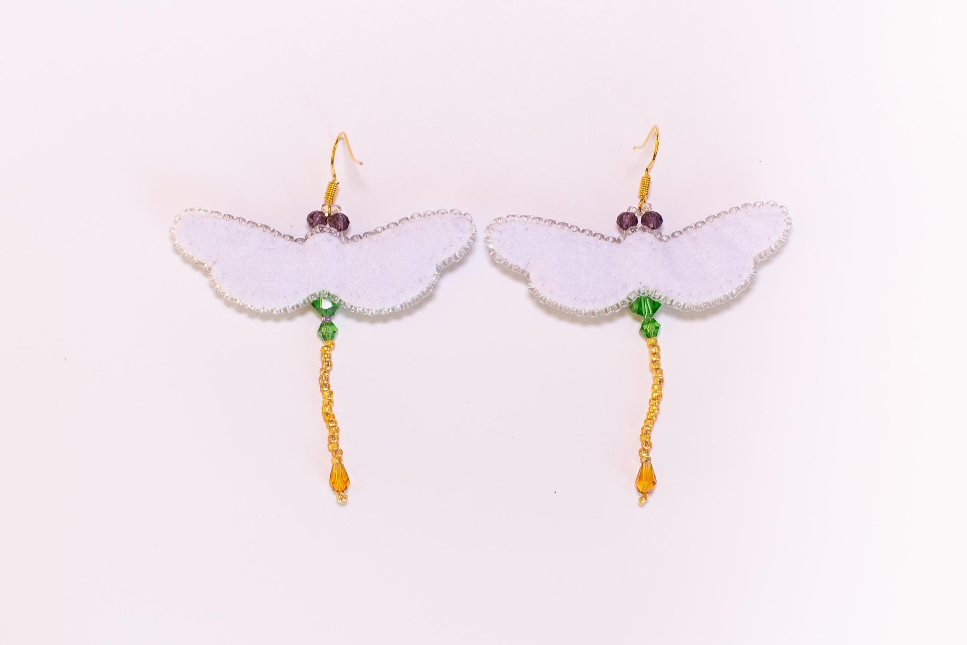 a pair of white earrings with green beads