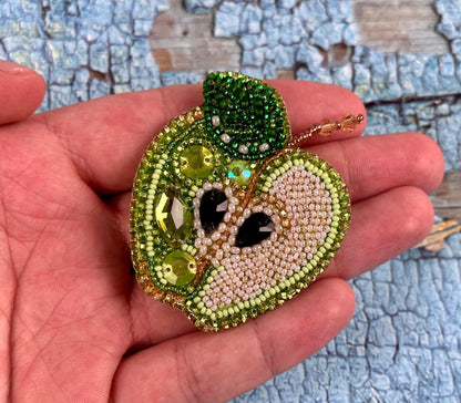 a hand holding a green apple with a face on it