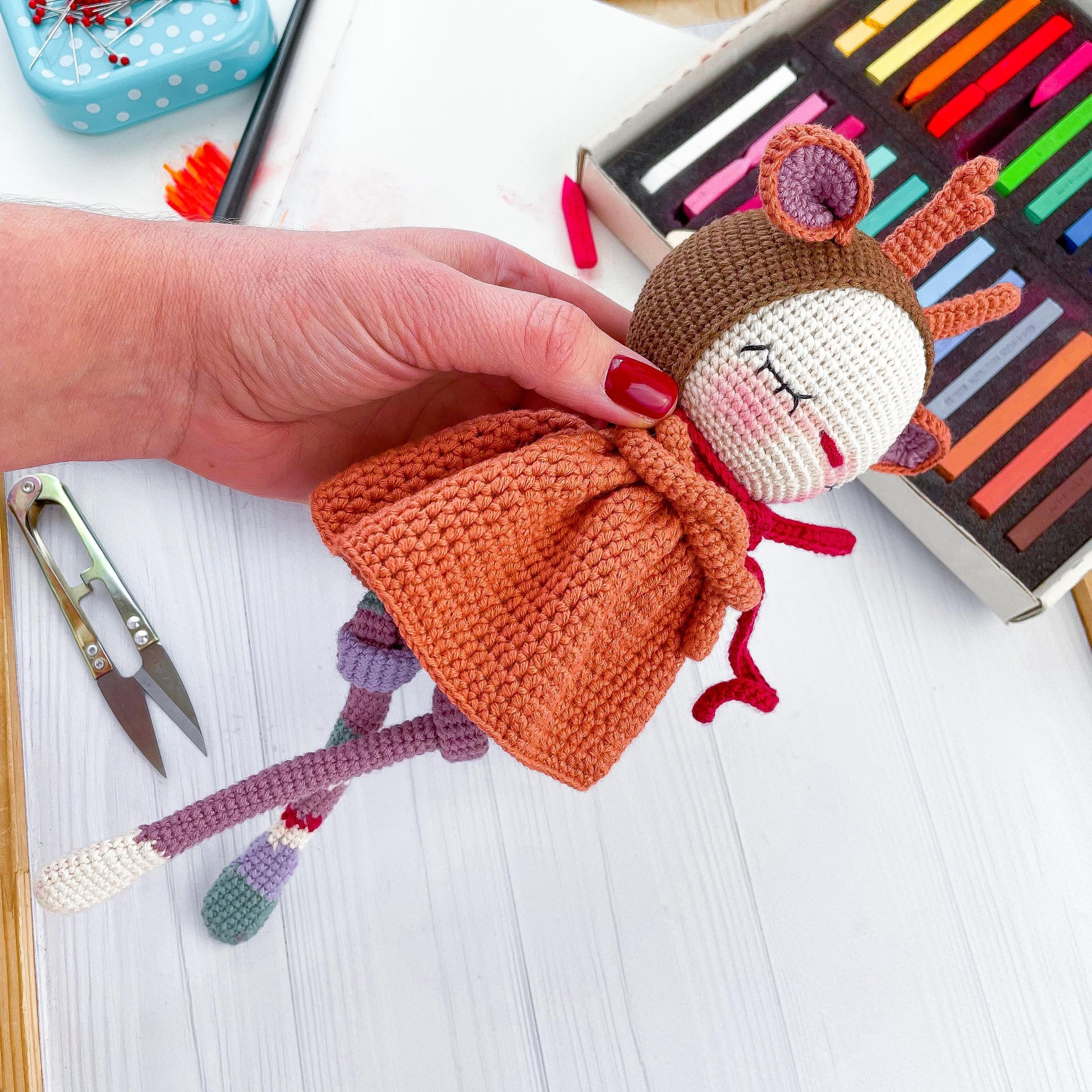 a crocheted doll being held by a person&#39;s hand