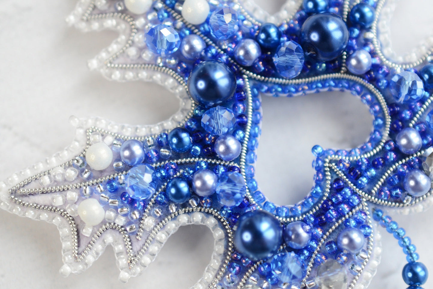 a close up of a blue and white beaded snowflake