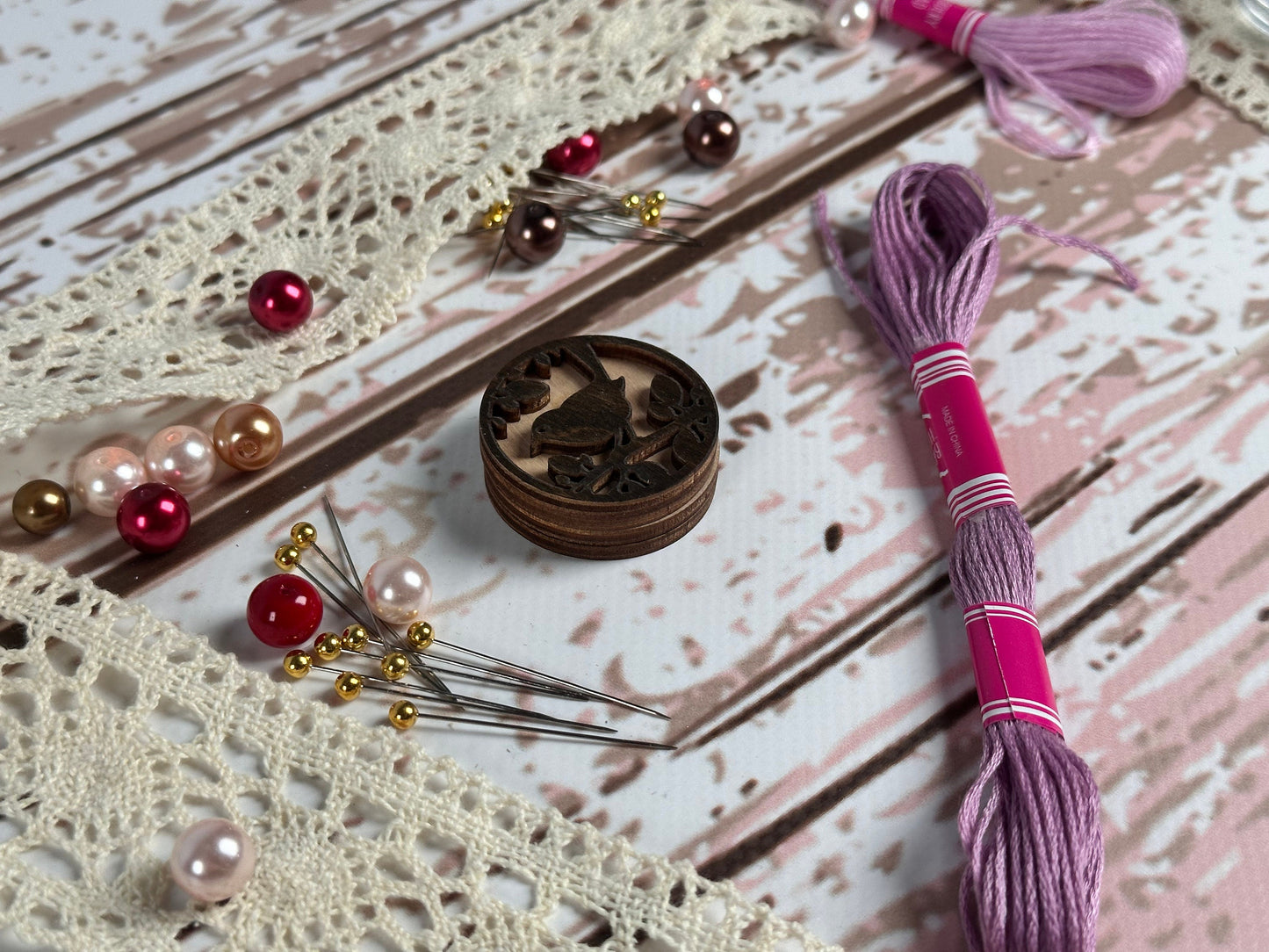 a pair of scissors, thread, beads, and a box on a table