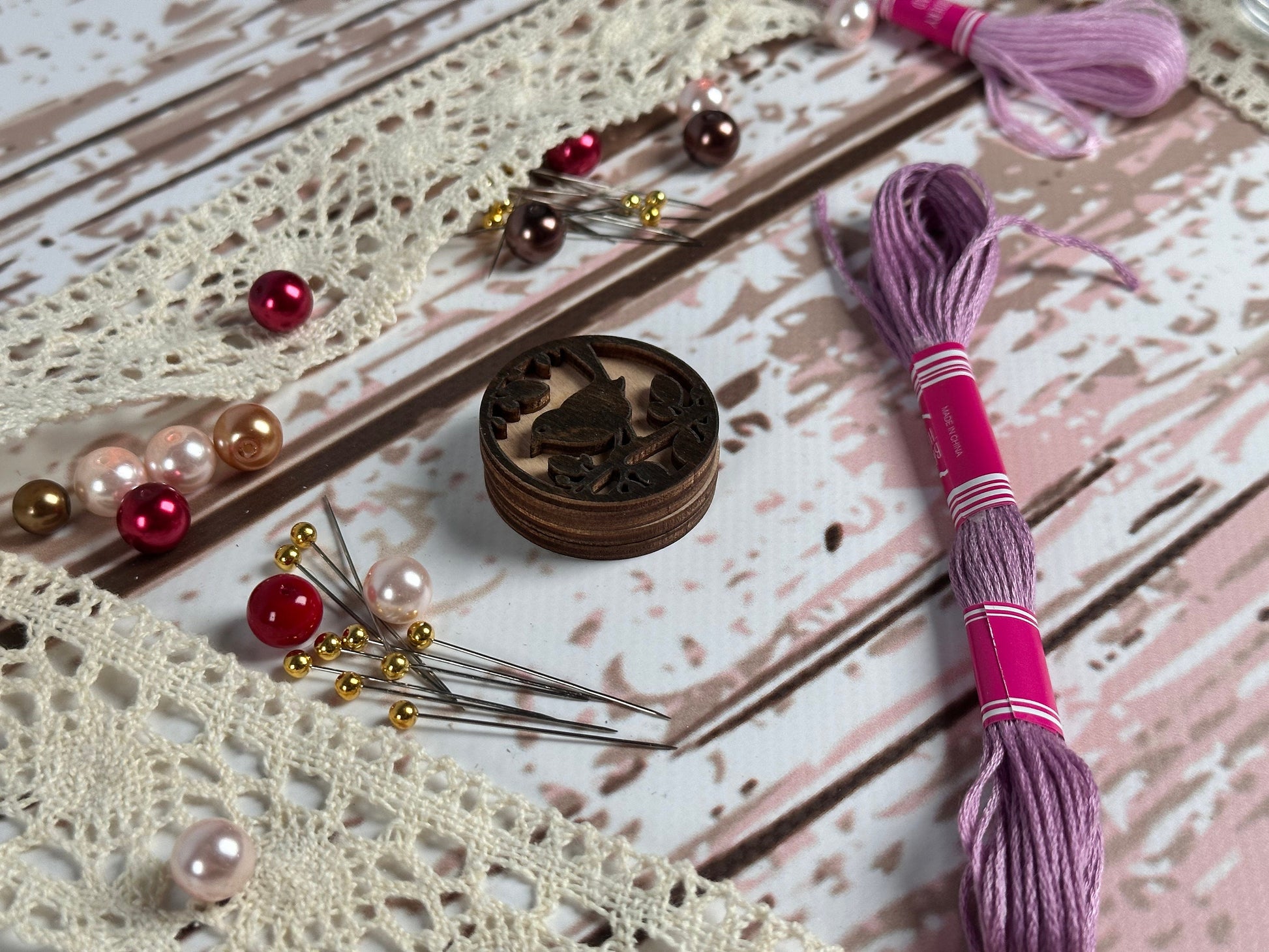 a pair of scissors, thread, beads, and a box on a table