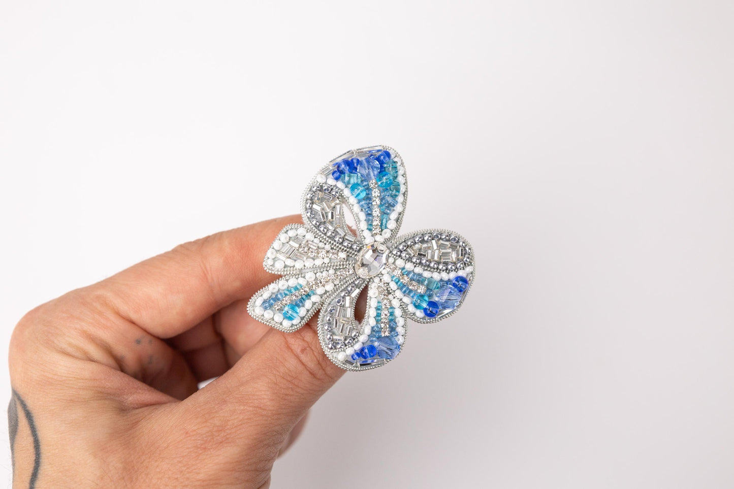 a hand holding a blue and white flower brooch