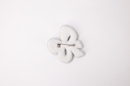 a white brooch with a white flower on it