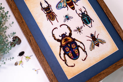 a framed artwork depicting a variety of colorful insects, including a large beetle and several smaller insects, all intricately detailed and vibrant.