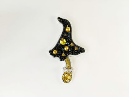 a black hat with gold beads hanging from a hook