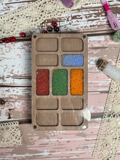 a wooden tray with different colors of beads