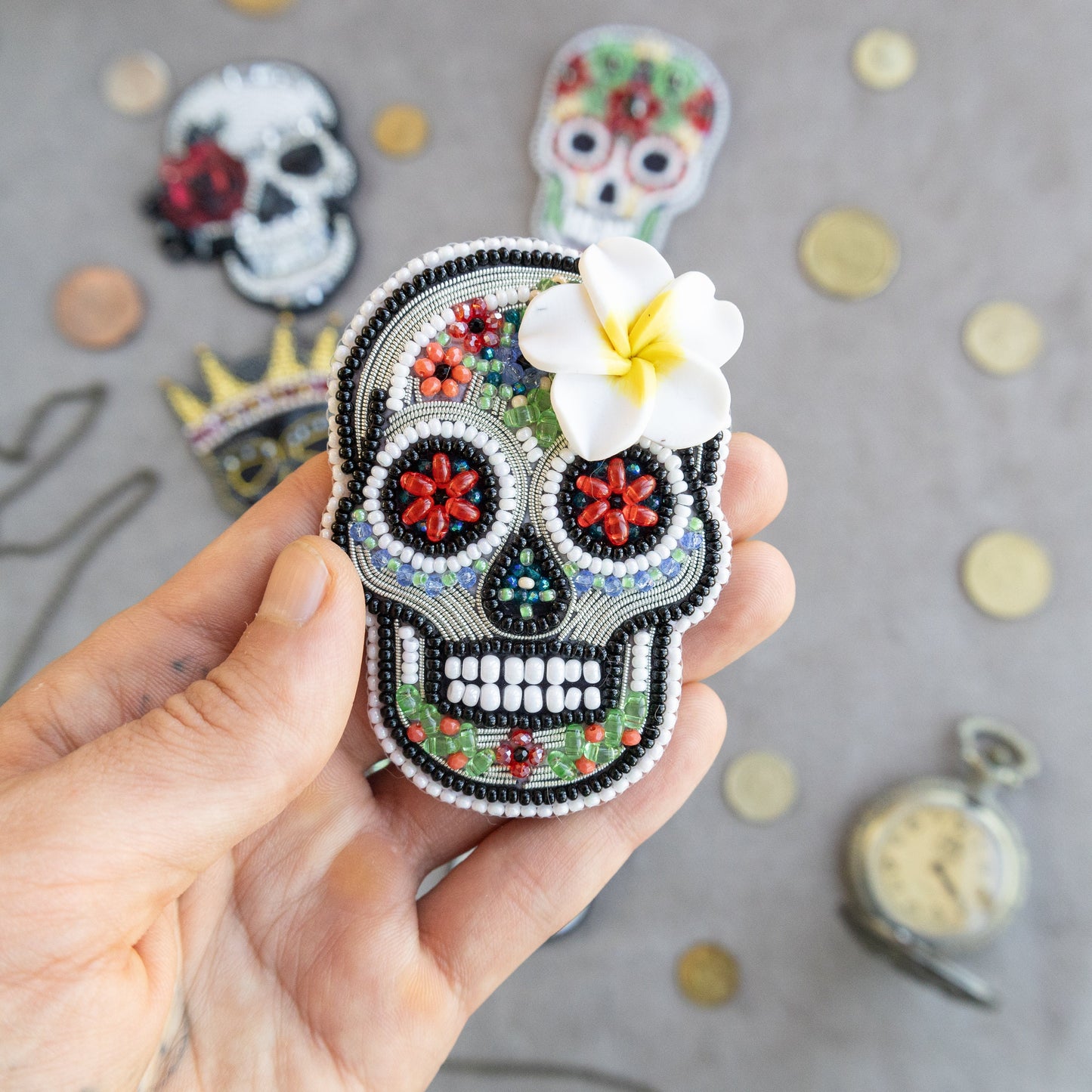 a hand holding a small sugar skull with a flower in it