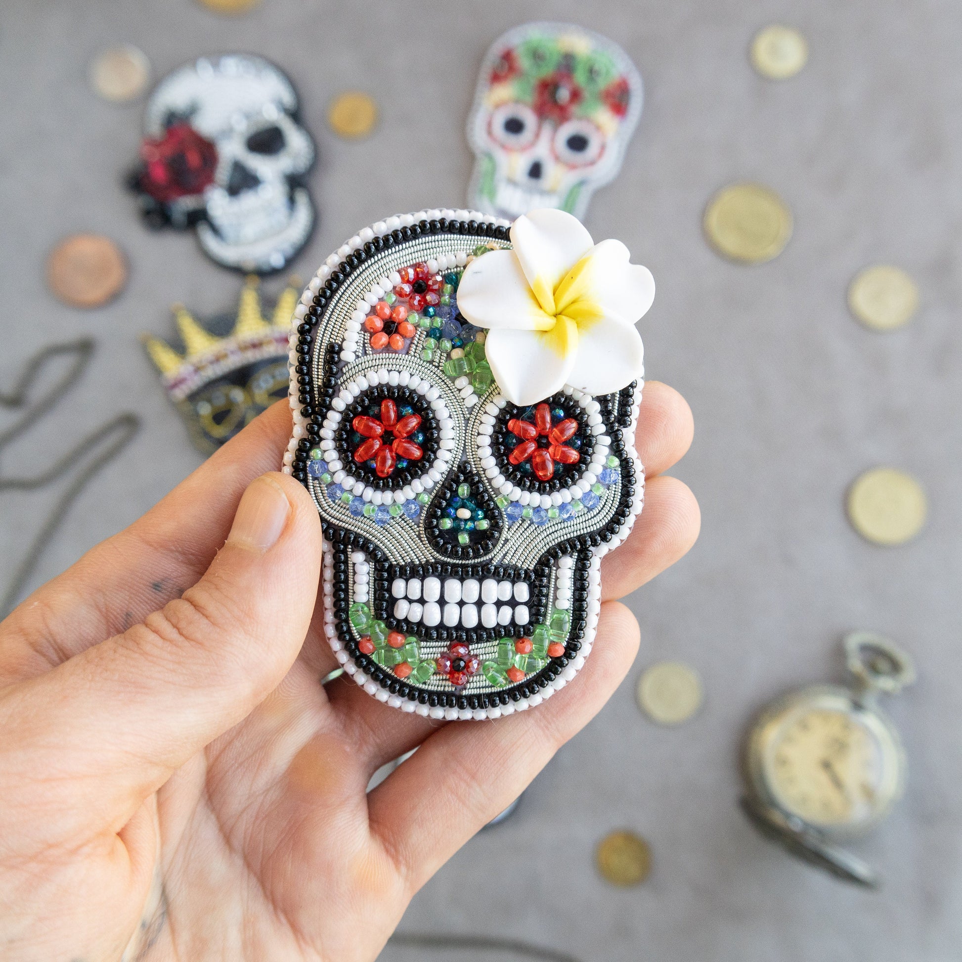 a hand holding a small sugar skull with a flower in it