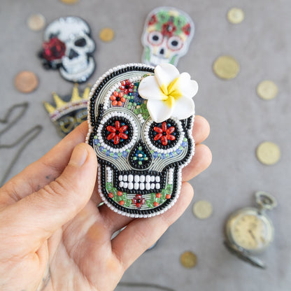 a hand holding a small sugar skull with a flower in it