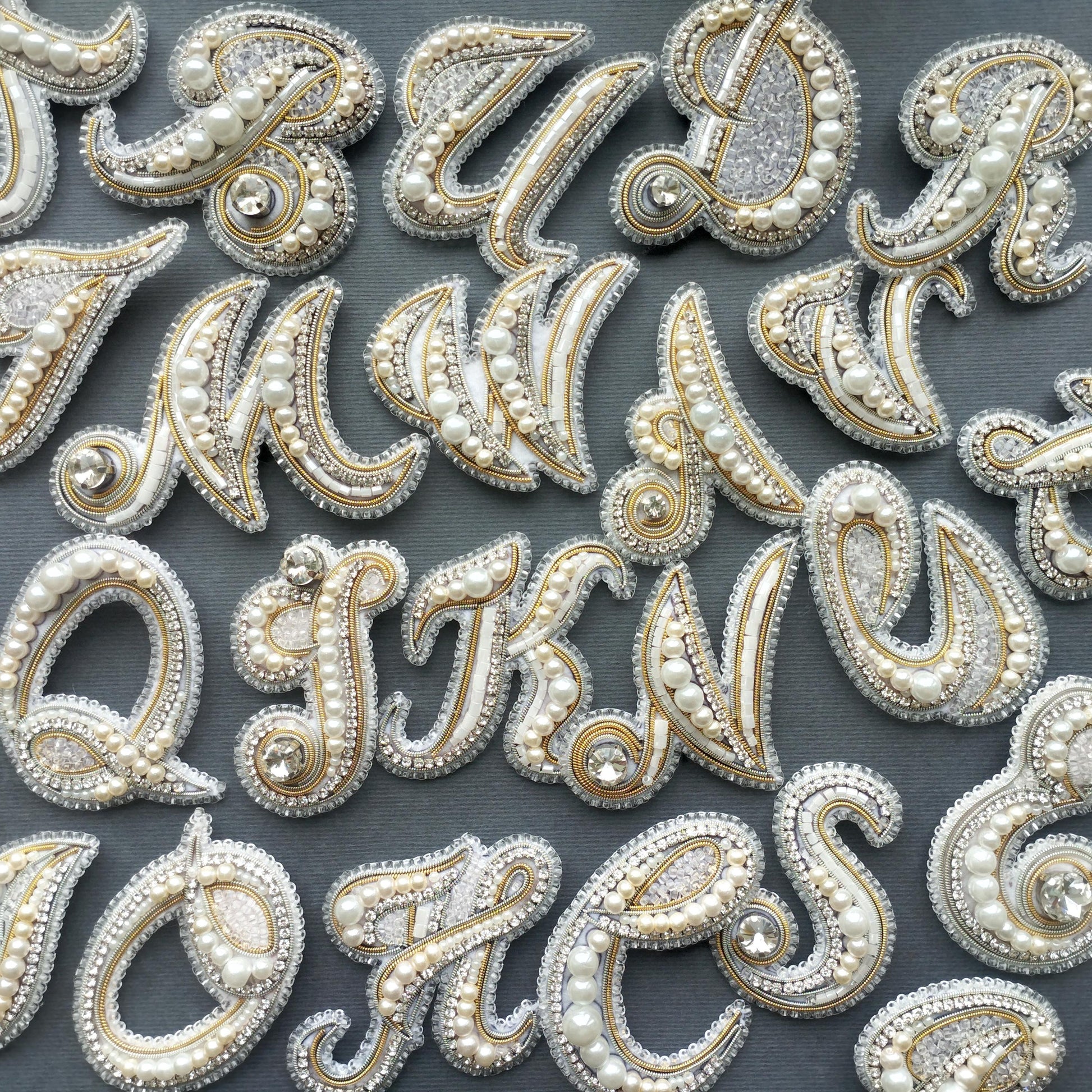a collection of ornate, bejeweled letters and numbers arranged on a dark background.