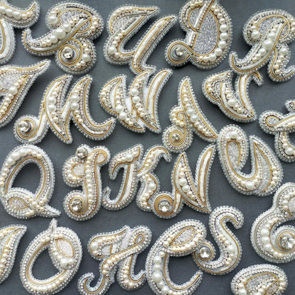 a collection of ornate, bejeweled letters and numbers arranged on a dark background.