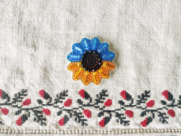 a close-up view of a decorative fabric with a colorful sunflower-shaped brooch prominently displayed in the center.