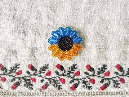 a close-up view of a decorative fabric with a colorful sunflower-shaped brooch prominently displayed in the center.