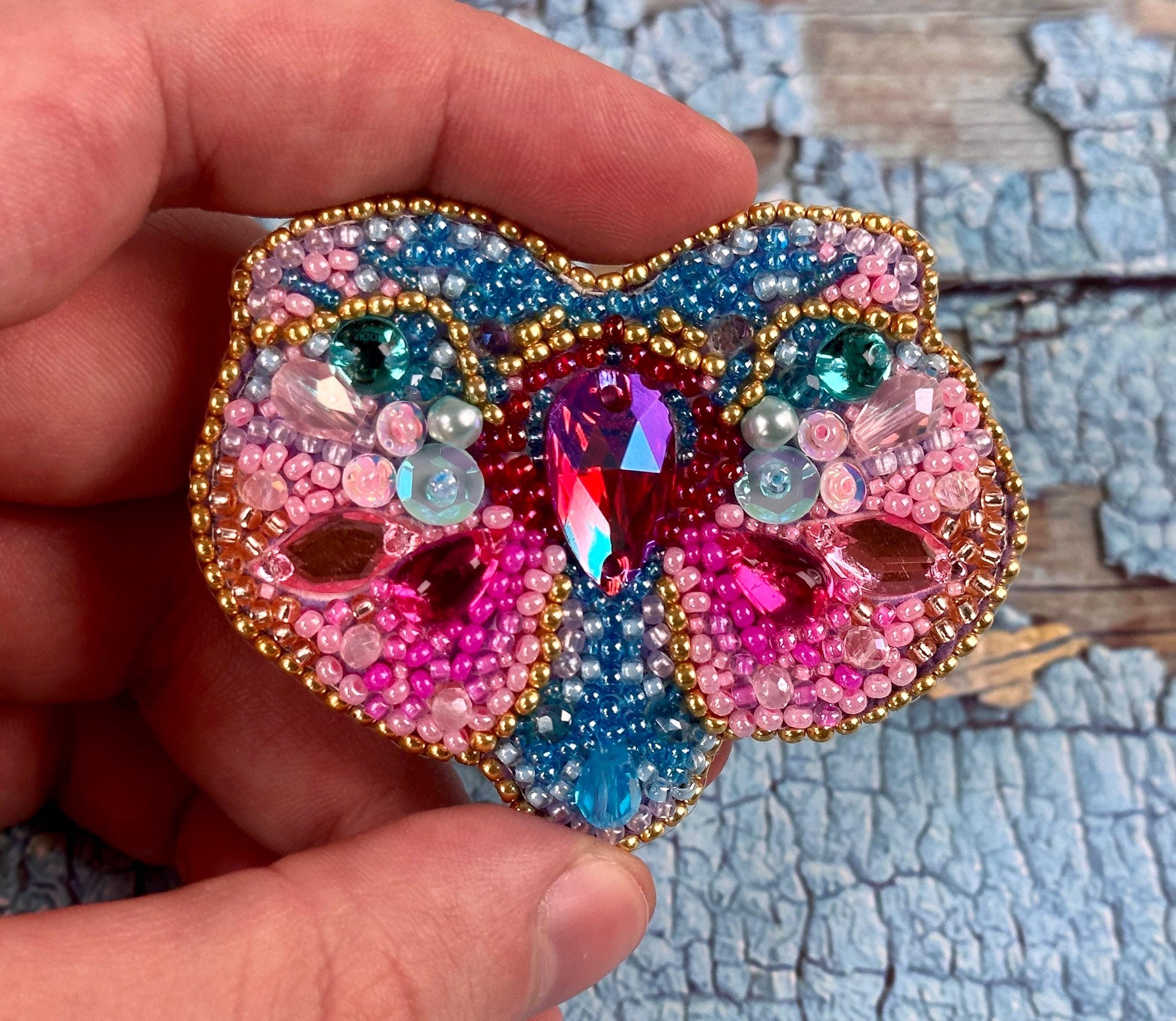 a person holding a colorful brooch in their hand