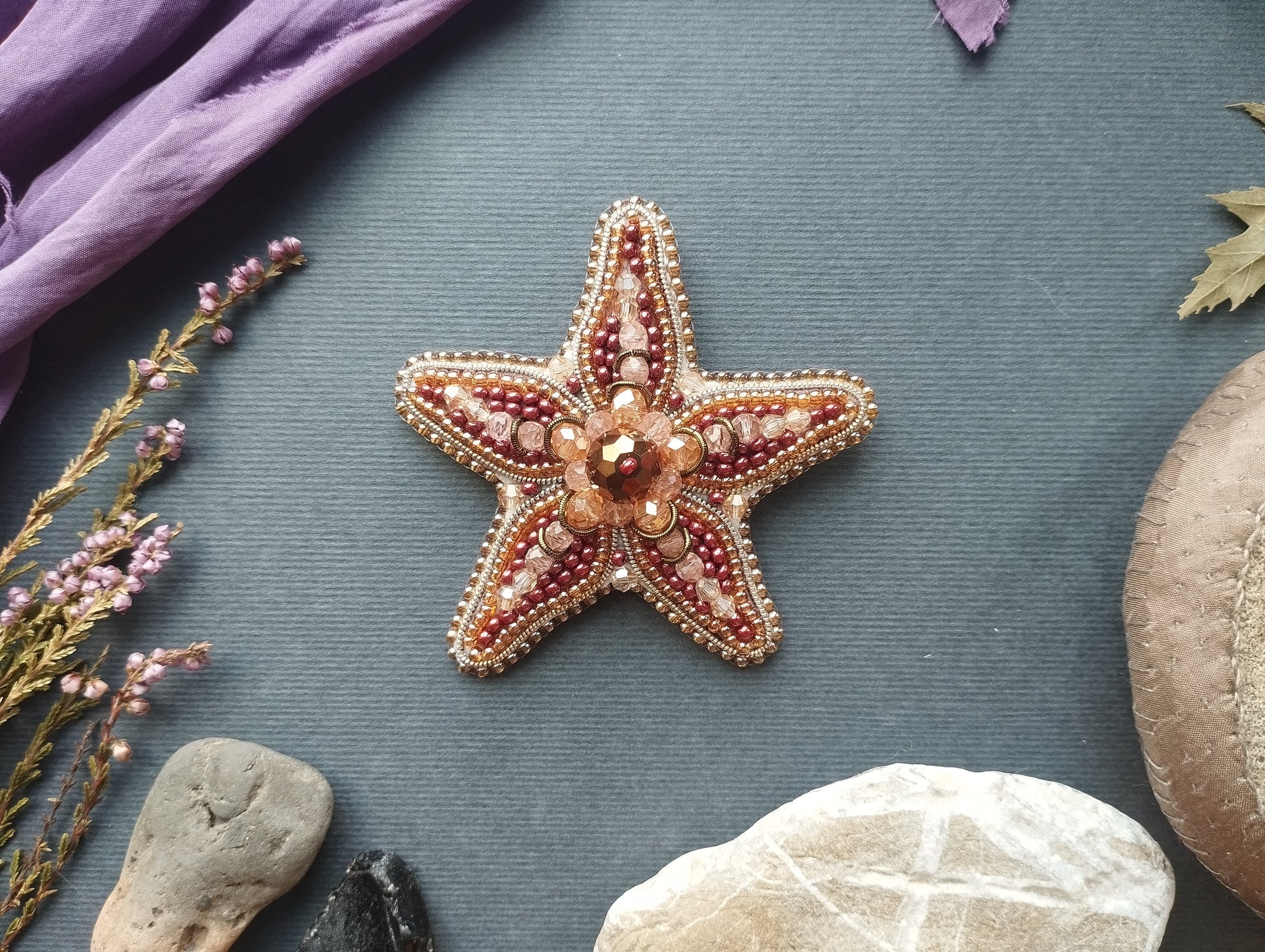 a starfish with a beaded design, surrounded by various natural elements such as rocks, leaves, and flowers.
