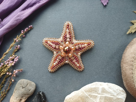 a starfish with a beaded design, surrounded by various natural elements such as rocks, leaves, and flowers.