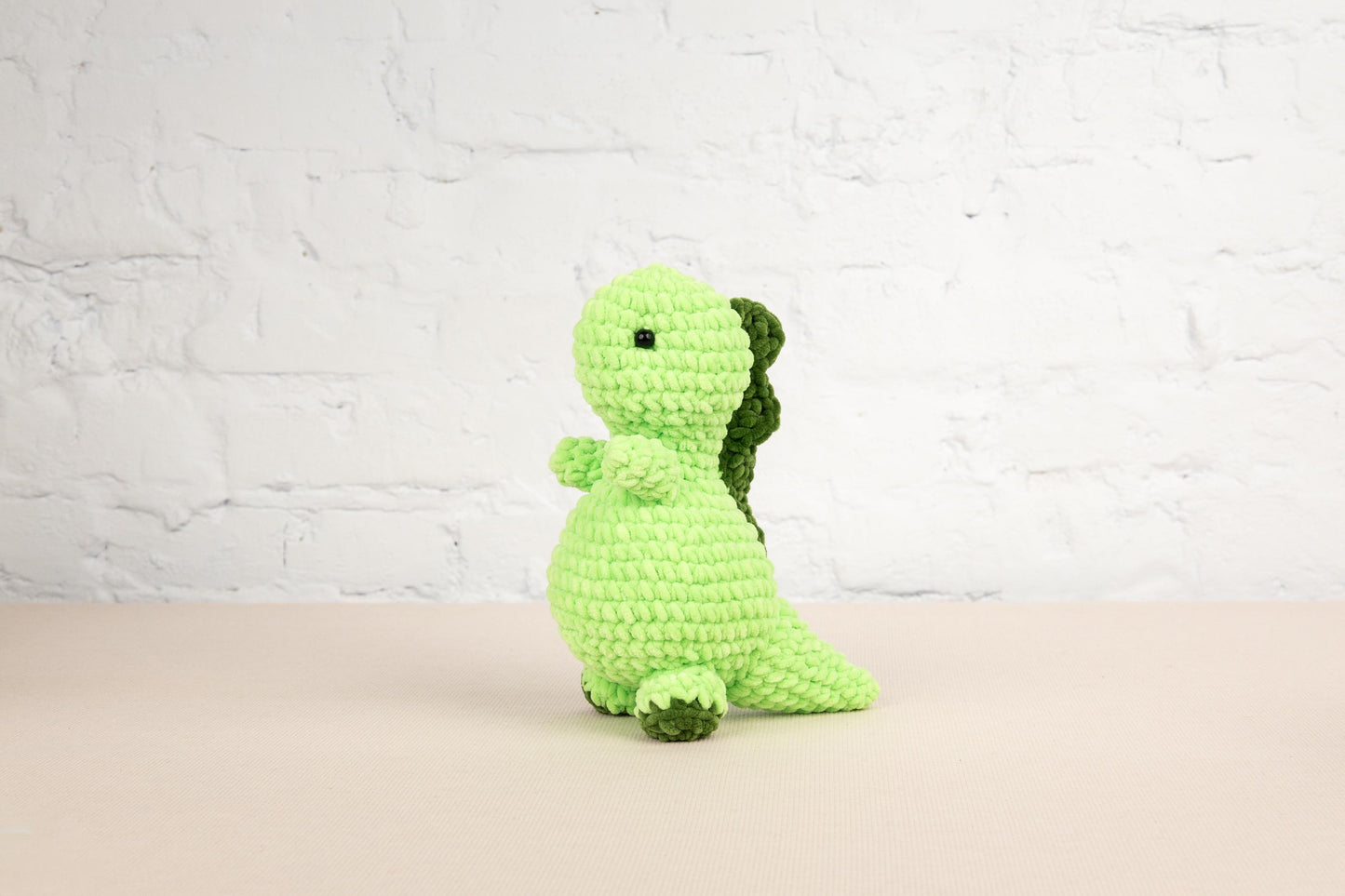 a green crocheted stuffed animal sitting on a table
