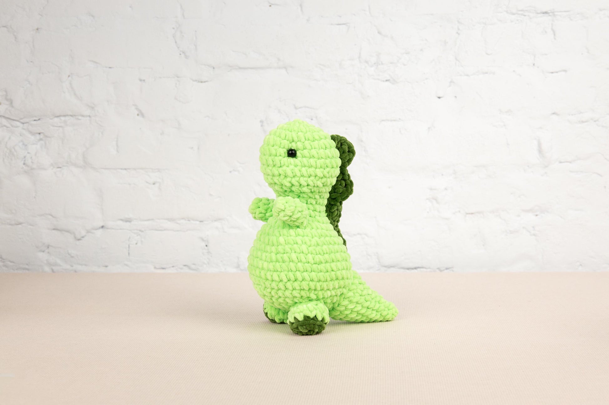 a green crocheted stuffed animal sitting on a table