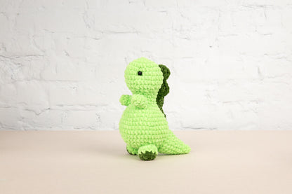 a green crocheted stuffed animal sitting on a table