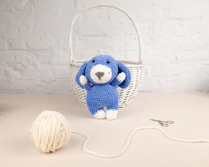 a blue teddy bear sitting next to a ball of yarn