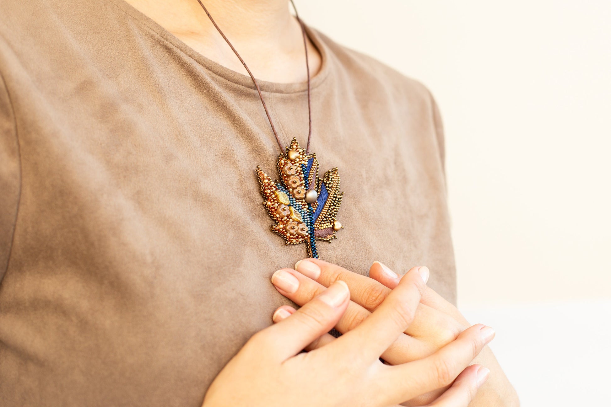 a woman wearing a brown shirt holding a necklace