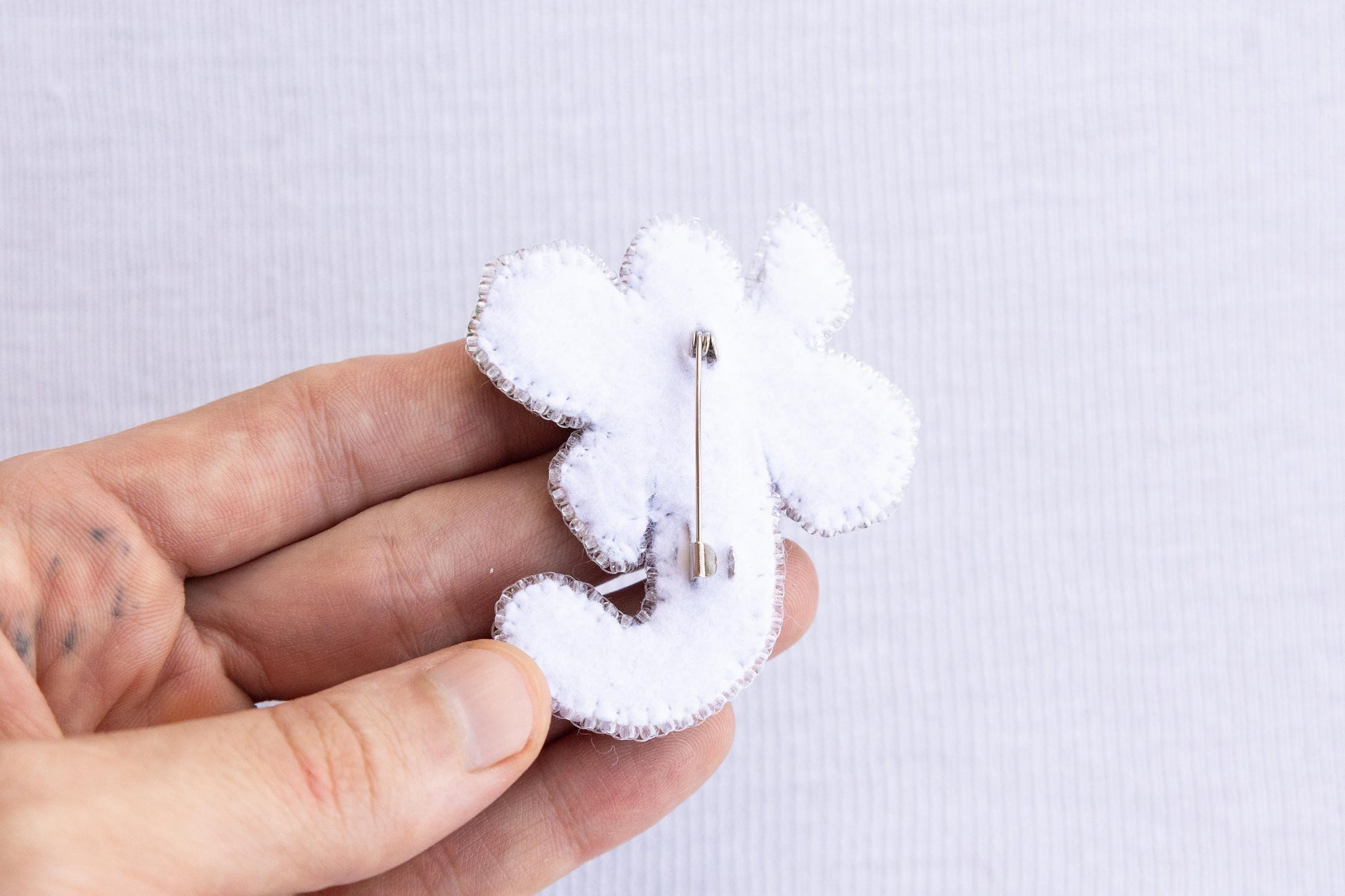 a person is holding a small white brooch