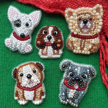 five embroidered dog brooches on a green background.