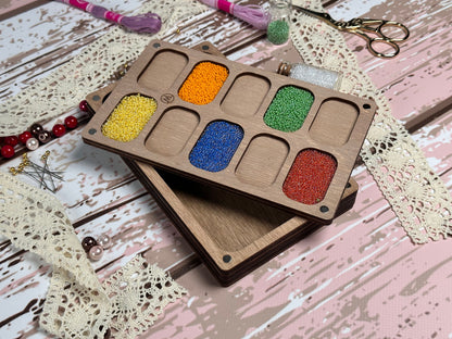 a wooden tray with six different colors of beads
