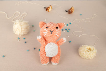 a crocheted cat sitting next to a ball of yarn