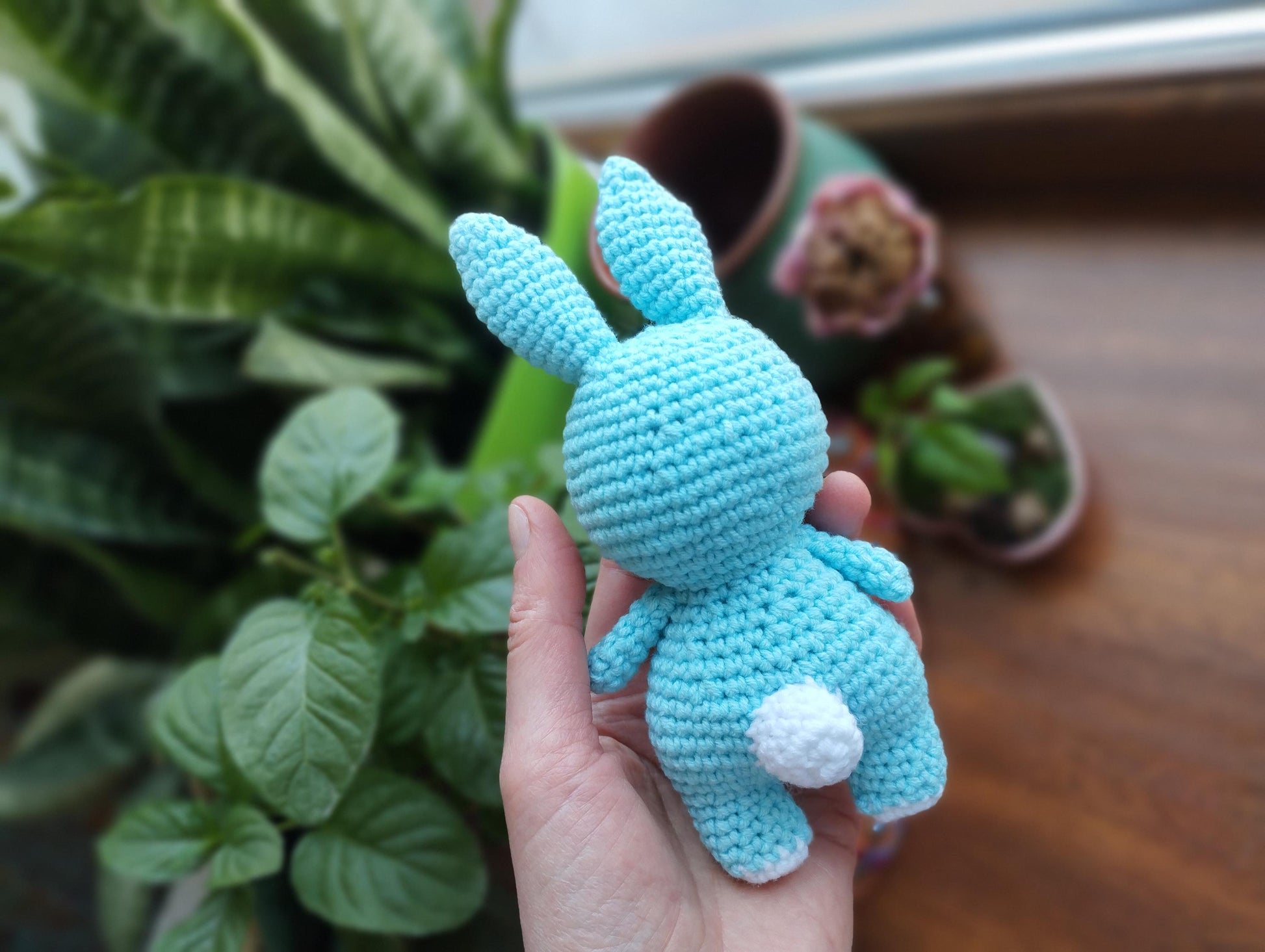 a hand holding a small crocheted blue bunny