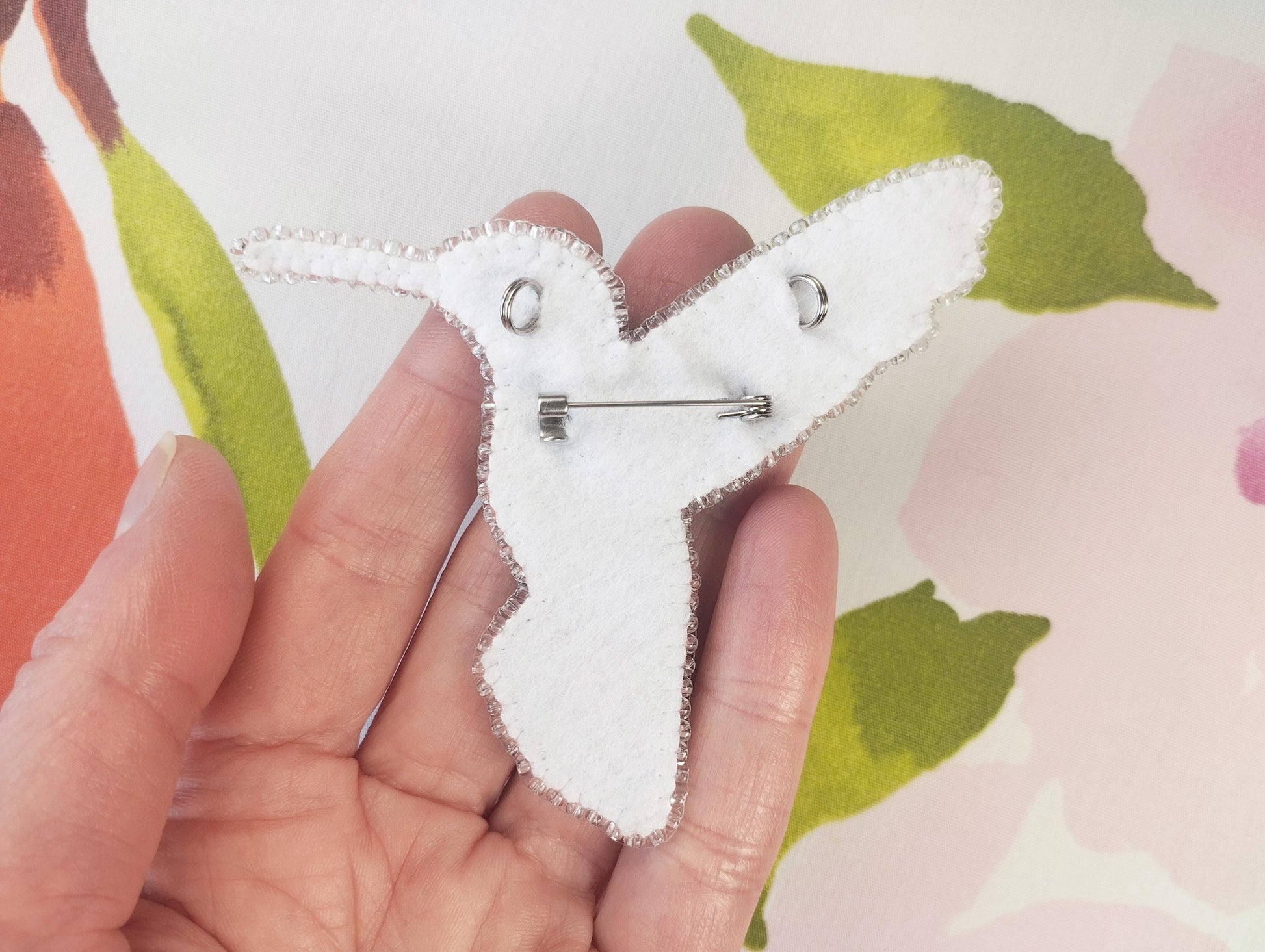 a person holding a piece of fabric with a pin in it