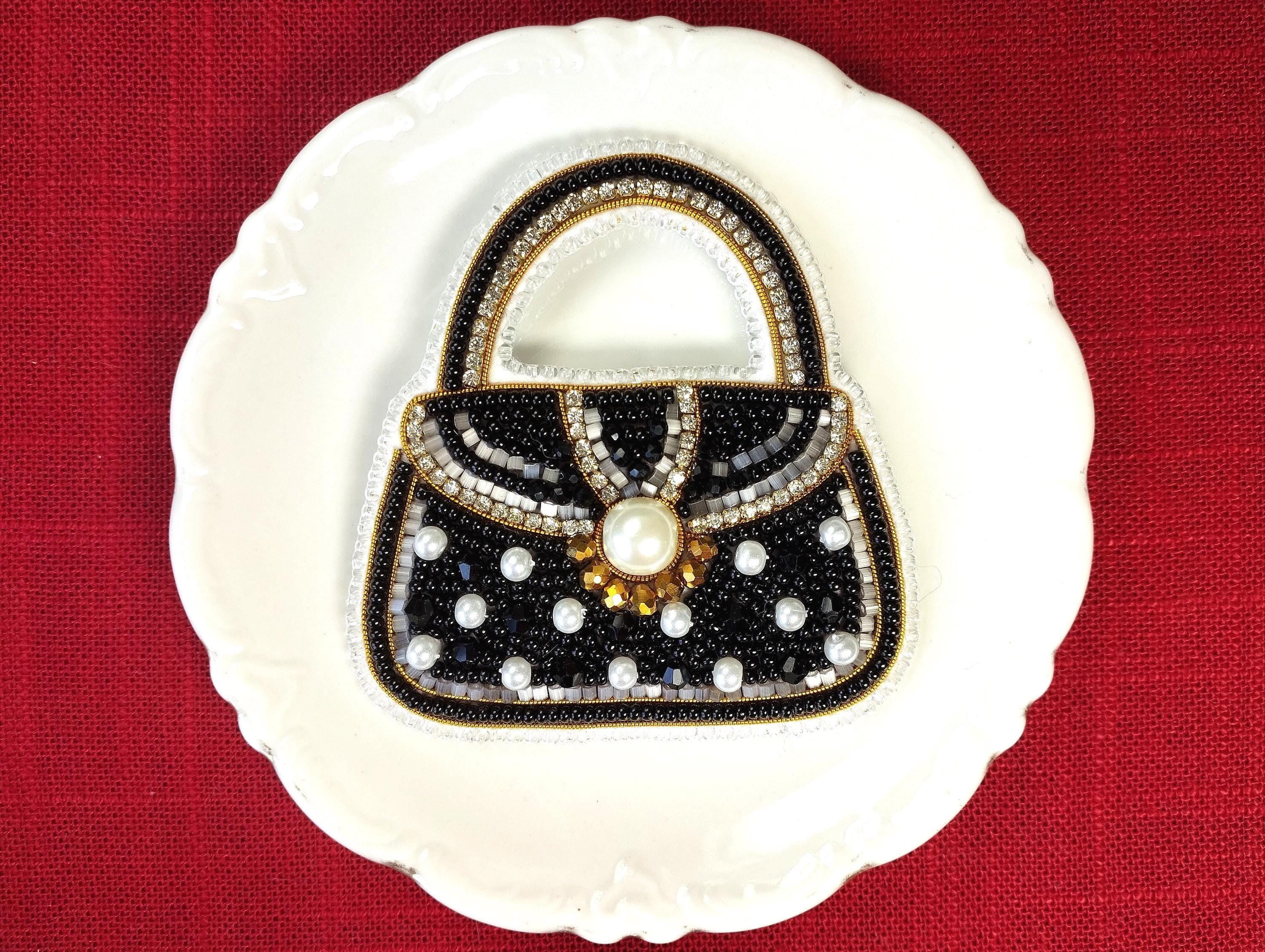 A white plate with a black and gold handbag-shaped design made of beads and pearls, placed on a red background.