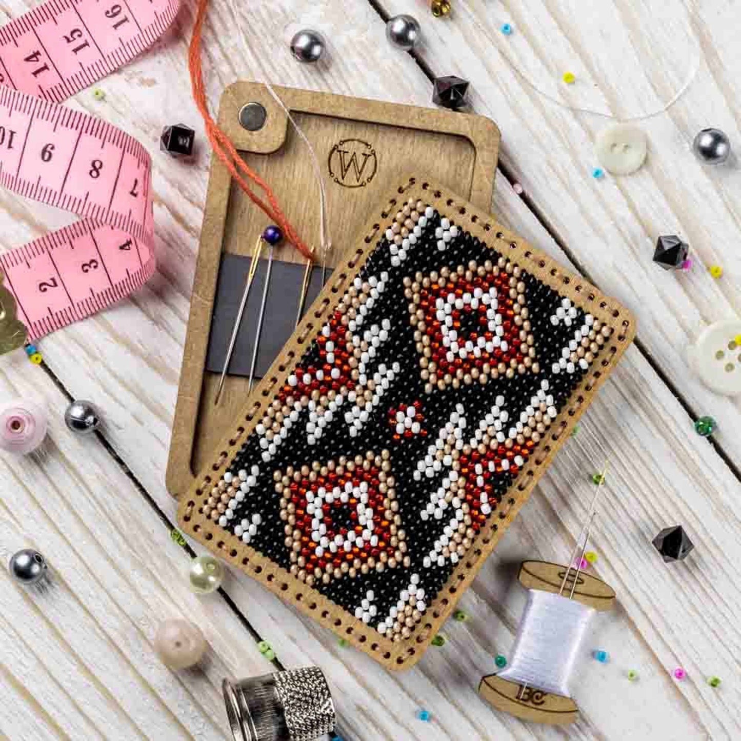 a piece of beaded art next to a measuring tape