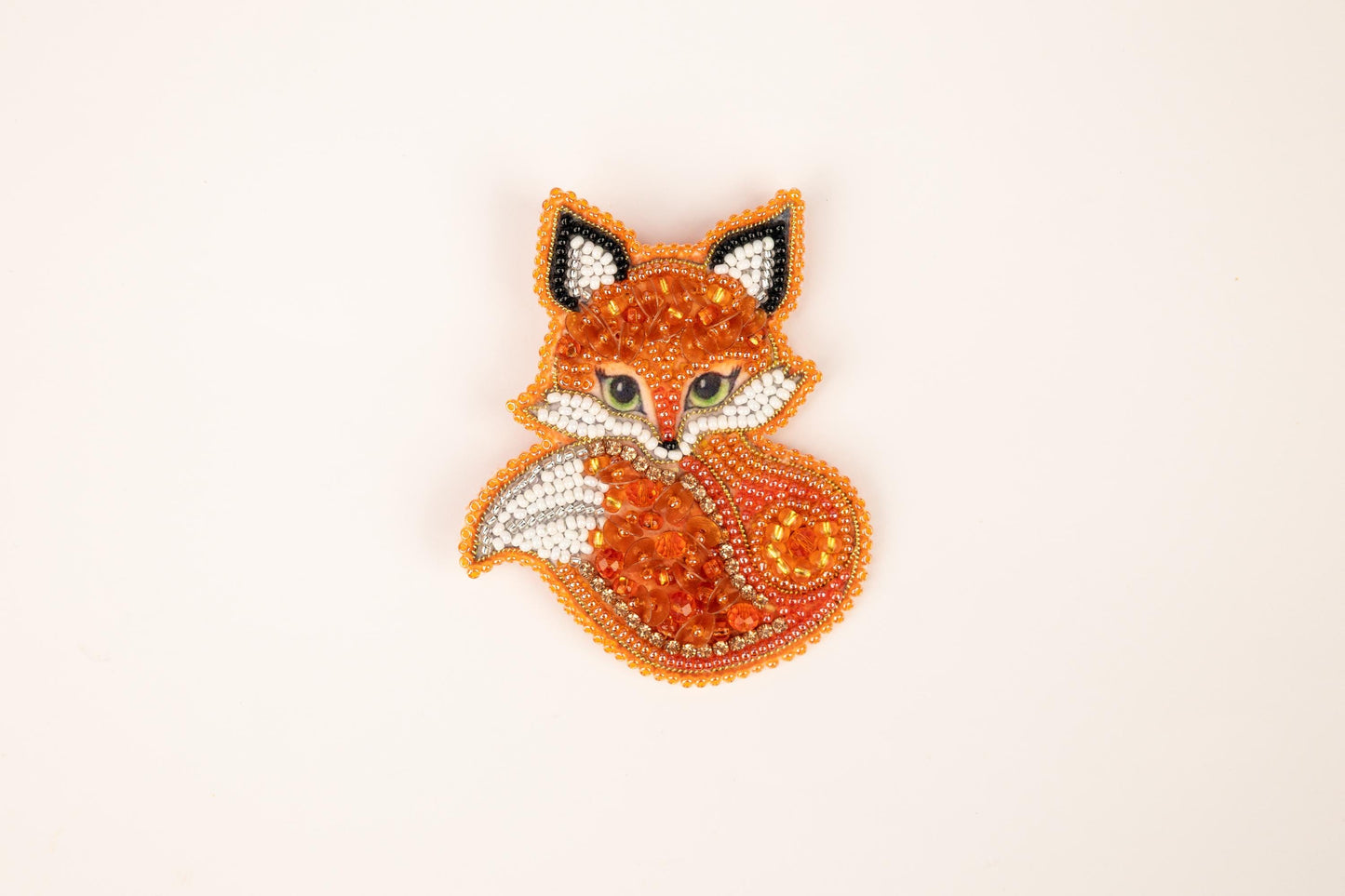 a beaded fox brooch sitting on top of a white surface