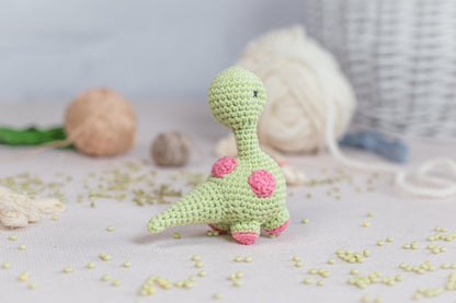 a crocheted toy of a dinosaur sitting on a table