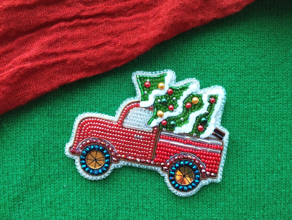A red truck decorated with Christmas ornaments and a Christmas tree is displayed on a green background.