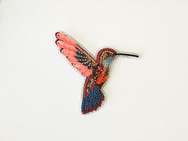a colorful bird made out of beads on a white surface