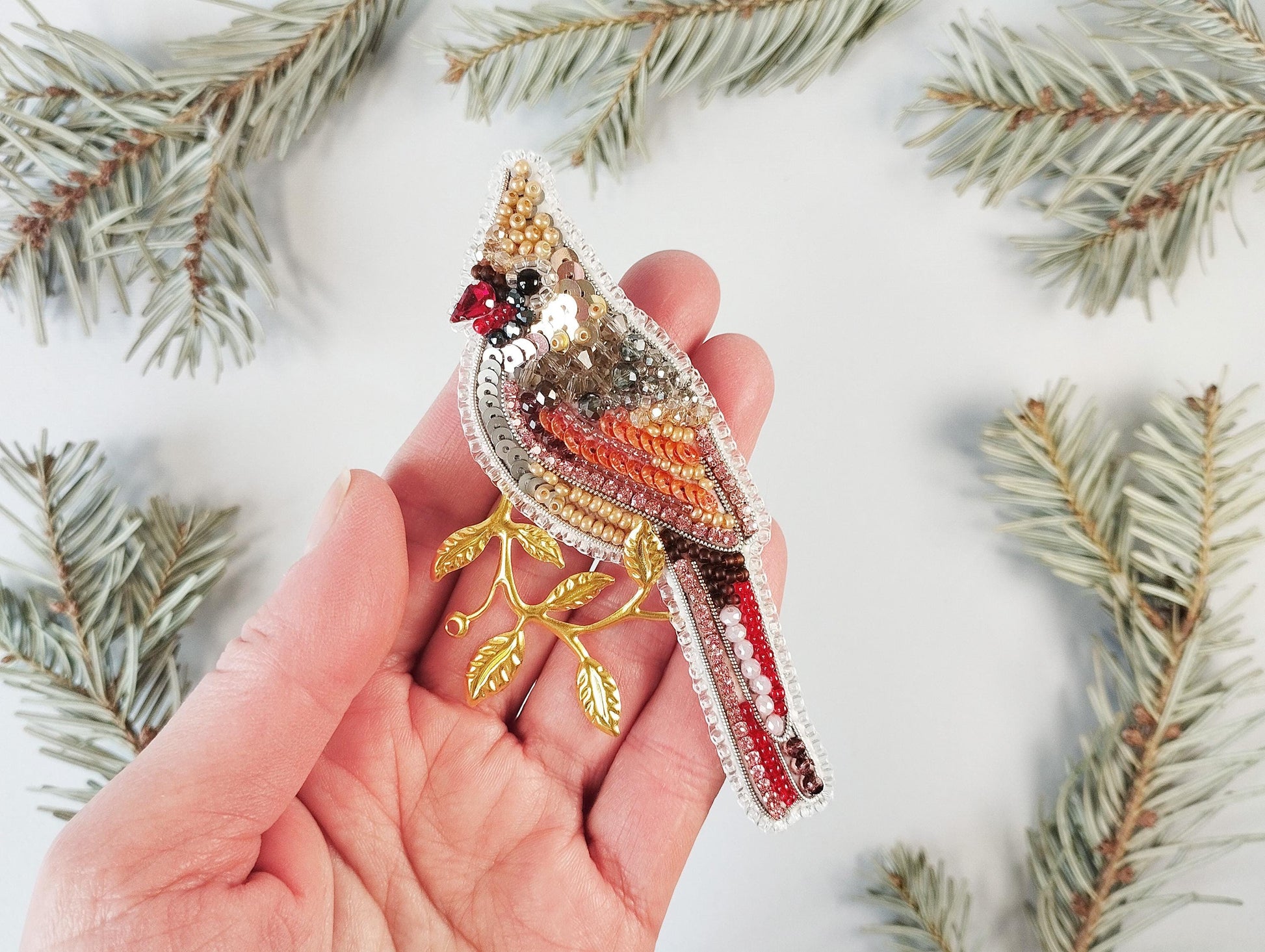 a person holding a bird brooch in their hand