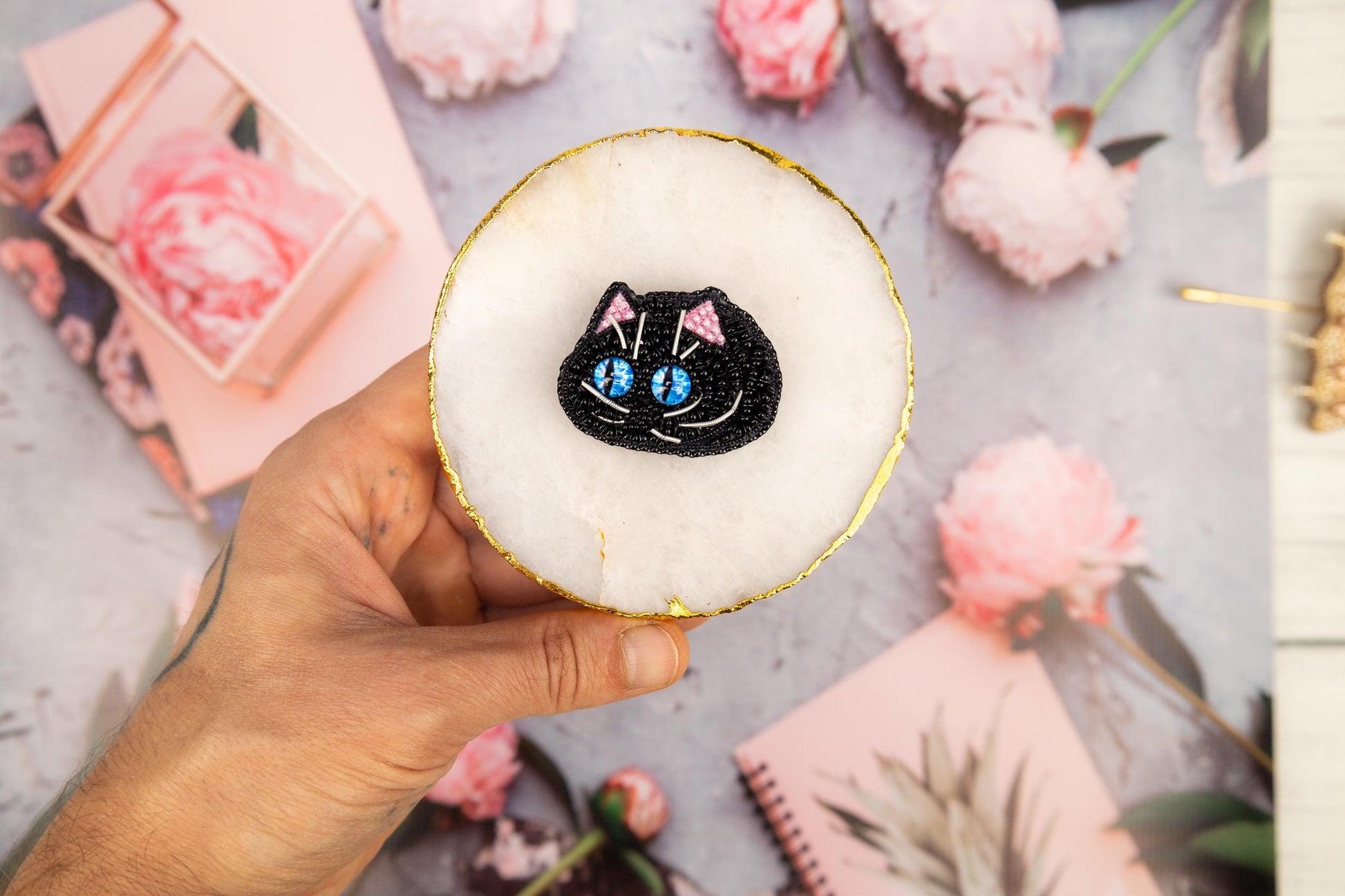 a person holding a cupcake with a black cat on it