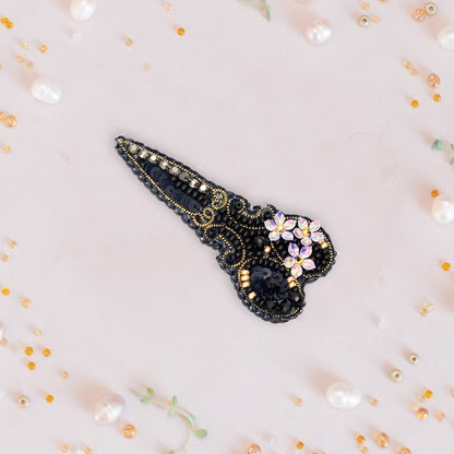 a black and gold brooch with flowers on it