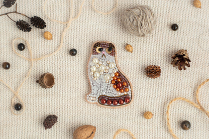 a mosaic of various objects, including a cat-shaped piece of art, pine cones, beads, and other natural elements, all arranged on a white background.